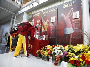 An Iowa State cheerleader signs a memorial card to honor slain student Celia Barquin Arozamena, seen in photo at right, before an NCAA college football game between Iowa State and Akron, Saturday, Sept. 22, 2018, in Ames, Iowa. Barquin, who was the 2018 Big 12 women's golf champion and Iowa State Female Athlete of the Year, was found Monday morning in a pond at a golf course near the Iowa State campus.