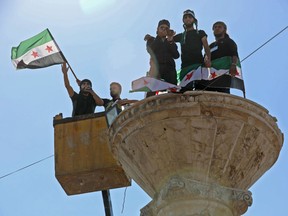 A Syrian protester wearing the colours of opposition shouts slogans in a microphone as he stands in a crane during an anti-government demonstration in the rebel-held town of Maaret al-Numan, in the north of Idlib province on September 28, 2018.