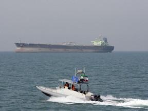 FILE-- In this July 2, 2012 file photo, an Iranian Revolutionary Guard speedboat moves in the Persian Gulf while an oil tanker is seen in background. As nuclear deal threatened, Iran's politics increasingly under pressure 40 years after Islamic Revolution. In response, President Hassan Rouhan has slowly replaced his message of rapprochement with the West with hard-line hints about Iran's ability to close off the Strait of Hormuz, through which a third of all oil traded by sea passes.