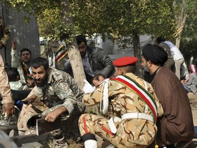 In this photo provided by the Iranian Students' News Agency, ISNA, Iranian armed forces members and civilians take shelter in a shooting during a military parade marking the 38th anniversary of Iraq's 1980 invasion of Iran, in the southwestern city of Ahvaz, Iran, Saturday, Sept. 22, 2018.