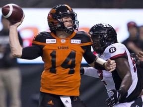 Ottawa Redblacks defensive lineman George Uko (92) looks on as BC Lions quarterback Travis Lulay (14) throws the ball during the first half of CFL football action in Vancouver, B.C., on Friday, Sept. 7, 2018.