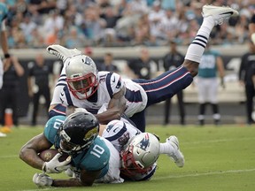 Jacksonville Jaguars wide receiver Donte Moncrief (10) is tackled by New England Patriots defensive back Jonathan Jones (31) and defensive back Nate Ebner, bottom right, after a reception during the first half of an NFL football game, Sunday, Sept. 16, 2018, in Jacksonville, Fla.