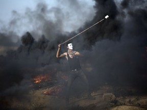 A Palestinian protester hurls stones at Israeli troops during a protest at the Gaza Strip's border with Israel, Friday, Sept.28, 2018.