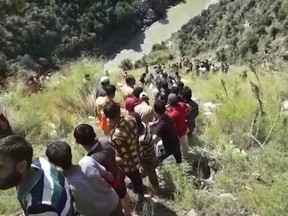 In this grab made from video provided by KK Productions, rescuers try to reach a bus that fell into a gorge in Kishtwar, about 217 kilometers (135 miles) southeast of Srinagar, Indian-controlled portion of Kashmir, Friday, Sept. 14, 2018. The bus fell off a road into a deep gorge killing more than a dozen people.