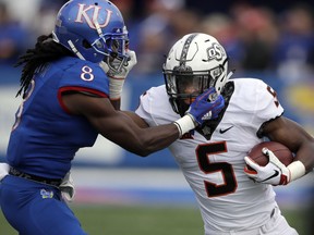 Oklahoma State running back Justice Hill (5) is tackled by Kansas cornerback Shakial Taylor (8) during the first half of an NCAA college football game in Lawrence, Kan., Saturday, Sept. 29, 2018.