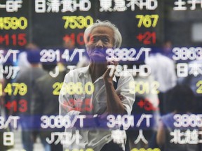 A man is reflected on the electronic board of a securities firm in Tokyo, Tuesday, Sept. 18, 2018. Asian markets were mixed on Tuesday after President Donald Trump ordered tariffs on $200 billion more in Chinese goods, ramping up tensions between the world's top two economies.