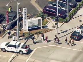 This photo from video provided by ABC7 Los Angeles shows people being evacuated from Kaiser Permanente Downey Medical Center, following reports of someone with a weapon at the facility in Downey, Calif., Tuesday, Sept. 11, 2018. Los Angeles County sheriff's officials say a suspect is in custody and deputies and police officers are methodically searching the complex. (ABC7 Los Angeles via AP)