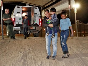 FILE - In this July 18, 2018 file photo, a Honduran man carries his 3-year-old son as his daughter and other son follow to a transport vehicle after being detained by U.S. Customs and Border Patrol agents in San Luis, Ariz. Border arrests figures for August 2018, are the latest reminder of how crossings have shifted over the last decade from predominantly Mexican men to Central American families and children. The number of family arrivals reached 15,955, a sharp increase from July that Customs and Border Protection Commissioner Kevin McAleenan said was one of the highest on record.