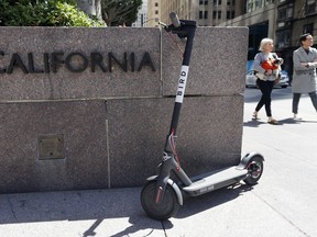 FILE - This April 17, 2018 file photo shows a motorized scooter parked in front of an office building in San Francisco. Gov. Jerry Brown signed legislation Wednesday, Sept. 19, 2018, requiring helmets only for people under age 18 while riding motorized scooters. It's a win for companies such as Bird and Lime that operate the popular scooters in major cities across California and the country.