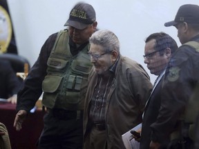 In this photo taken through a window, Abimael Guzman, founder and leader of the Shining Path guerrilla movement, arrives to court at a military base in Callao, Peru, Tuesday, Sept. 11, 2018. On Tuesday, the historic leader of the terrorist group Shining Path will be sentenced for his role in a 1992 car bomb that killed 25 people in Lima.