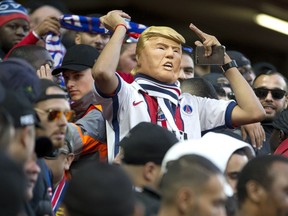 A PSG fan wears a mask depicting US President Donald Trump in the stands ahead of the Champions League Group C soccer match between Liverpool and Paris-Saint-Germain at Anfield stadium in Liverpool, England, Tuesday, Sept. 18, 2018.