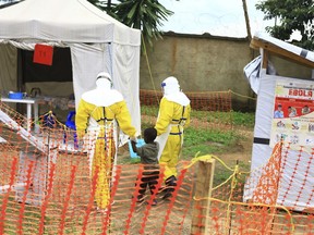 FILE - In this Sunday, Sept 9, 2018 file photo, health workers walk with a boy suspected of having the Ebola virus at an Ebola treatment centre in Beni, Eastern Congo. The World Health Organization says the risk of the deadly Ebola virus spreading from Congo is now "very high" after two confirmed cases were discovered near the Uganda border. The outbreak in northeastern Congo is larger than the previous one in the northwest and more complicated for health officials with insecurity from rebel groups. As of Friday, Sept. 28 there were 124 confirmed Ebola cases including 71 deaths.