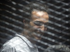 Mahmoud Abu Zaid, a photojournalist known as Shawkan stands inside a cage in an Egyptian Court in Cairo, Egypt, Saturday Sept. 8, 2018. In a case involving 739 defendants, the Egyptian court on Saturday sentenced 75 people to death, including top leaders of the outlawed Muslim Brotherhood, for their involvement in a 2013 sit-in protest. Mahmoud Abu Zaid, a photojournalist also known as Shawkan whose case was embraced by rights groups, received five years imprisonment, meaning he will walk free for time served.