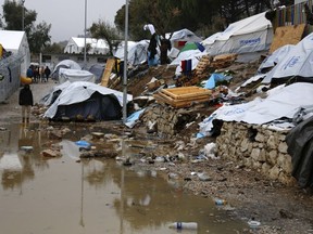 FILE - In this Tuesday, Jan. 10, 2017 file photo, a refugee stands next to a pool of mud at Moria refugee camp on the eastern Greek island of Lesbos. Greek regional authorities are threatening to shut an infamous migrant camp on the Aegean Sea island of Lesbos unless the government takes quick action to improve conditions there. The northern Aegean regional authority says the Moria camp is "unsuitable and a threat to public health and the environment."