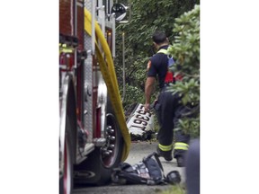 A firefighter stands near the wreckage of a single-engine plane behind a home on Minchin Drive, Saturday, Sept. 15, 2018, in Woburn, Mass. Officials said Dr. Michael Graver and Jodi Cohen were killed in the crash. The plane had departed from Republic Airport in Farmingdale, N.Y.,  and was en route to Laurence G. Hanscom Field in Bedford, Mass., about four miles from the crash site.