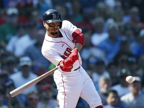 Boston Red Sox's Mookie Betts hits a sacrifice fly that scored Rafael Devers during the third inning of a baseball game against the New York Mets in Boston, Sunday, Sept. 16, 2018.