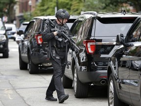 A Boston police special operations law enforcement officer carries an assault-style rifle near where police say an officer was shot, Sunday, Sept. 23, 2018, in Boston's South End neighborhood. Police say the suspect in the shooting, that they say resulted in the officer suffering non-life-threatening injuries, has been taken into custody.