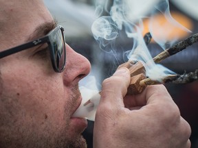 Brandon Bartelds smokes three joints at once while attending the 4-20 annual marijuana celebration, in Vancouver, B.C., on Friday April 20, 2018.