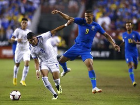 El Salvador defender Roberto Dominguez, left, chases after the ball alongside Brazil forward Richarlison in the first half of a soccer match, Tuesday, Sept. 11, 2018, in Landover, Md.