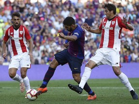FC Barcelona's Luis Suarez, center, duels for the ball against Athletic Bilbao's Mikel San Jose during the Spanish La Liga soccer match between FC Barcelona and Athletic Bilbao at the Camp Nou stadium in Barcelona, Spain, Saturday, Sept. 29, 2018.