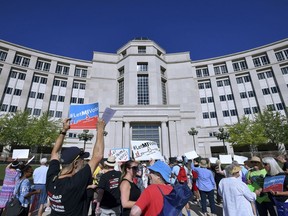 FILE- In a July 18, 2018 file photo demonstrators rally outside the Michigan Hall of Justice in Lansing, Mich., where the Michigan Supreme Court heard arguments about whether voters in November should be able to pass a constitutional amendment that would change how the state's voting maps are drawn or whether such changes could only be adopted at a rarely held constitutional convention.