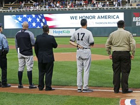 Players from both teams, including New York Yankees manager Aaron Boone (17), joined with police and first responders during the national anthem following a tribute to 9/11 victims and survivors prior to a baseball game between the Minnesota Twins and the Yankees, Tuesday, Sept. 11, 2018, in Minneapolis. Tom Barnett Jr. was aboard Flight 93 which went down in Pennsylvania.