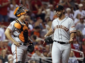 San Francisco Giants catcher Nick Hundley, left, looks at starting pitcher Madison Bumgarner as Bumgarner gestures following a score by the St. Louis Cardinals during the fifth inning of a baseball game Friday, Sept. 21, 2018, in St. Louis.
