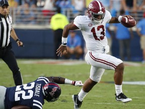 Alabama quarterback Tua Tagovailoa (13) evades a tackle by Mississippi defensive end Tariqious Tisdale (22) during the first half of their NCAA college football game, Saturday, Sept. 15, 2018, in Oxford, Miss.