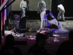 A crime scene worker covers up one of the bodies of victims of a shooting in Garibaldi Plaza, in Mexico City, Friday Sept. 14, 2018. Mexican authorities say four people have been killed and nine wounded in a shooting at the capital's emblematic Garibaldi Plaza, a popular spot for tourists.