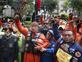 Rescue workers stand with with raised fists and in silence, in front of a 1985 earthquake memorial during a ceremony marking that quake's 33rd anniversary and last year's 7.1 magnitude earthquake, in Mexico City, Wednesday, Sept. 19, 2018. The rescue workers, known as "topos," are a voluntary civil brigade, who were created during the 1985 earthquake that left at least 9,500 dead.