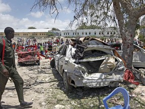 A Somali soldier walks near the wreckage of vehicles at the scene of a blast outside the compound of a district headquarters in the capital Mogadishu, Somalia Sunday, Sept. 2, 2018. A Somali police officer says a number of people are wounded after a suicide bomber detonated an explosives-laden vehicle at a checkpoint outside the headquarters after being stopped by security forces.