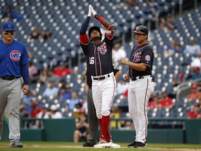 Chicago Cubs first baseman Anthony Rizzo (44), left, and Washington Nationals' first base coach Tim Bogar, right, look on as Nationals' Victor Robles (16) reacts after getting safely to first after batting in the third inning of a baseball game against the Chicago Cubs, Thursday, Sept. 13, 2018, in Washington.