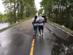 Famous Roberts and wife Latonya Green walk away from floodwaters left by Hurricane Florence on NC 41 in Trenton, N.C., on Monday, Sept. 17, 2018. The couple chose to stay in Trenton, partly because the storm had been downgraded from a Category 5 to a Category 1, but the flooding forced them to leave.