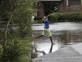 A child jumps a flooded street at Trent Court Apartments as surge water from the Trent River overflows sections of the neighborhood in New Bern, N.C. Thursday, Sept. 13, 2018. Hurricane Florence already has inundated coastal streets with ocean water and left tens of thousands without power, and more is to come.