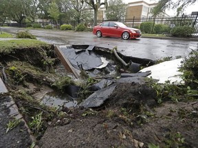 A car travels past a sinkhole in downtown Wilmington, N.C., after Hurricane Florence traveled through the area Sunday, Sept. 16, 2018.