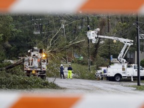 Duke Energy employees work on removing trees and restoring power to a road closed in Wilmington, N.C., after Hurricane Florence traveled through the area Sunday, Sept. 16, 2018.