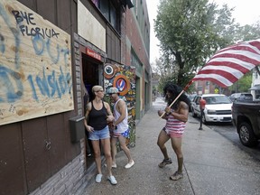 Jeff Egyp carries an American flag as he arrives at the Barbary Coast bar in downtown Wilmington, N.C., as the Florence threatens the coast Thursday, Sept. 13, 2018.