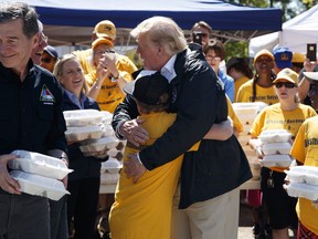 President Donald Trump hugs a young man while handing out prepackaged meals at Temple Baptist Church in an area impacted by Hurricane Florence, Wednesday, Sept. 19, 2018, in New Bern, N.C.