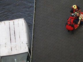 U.S. Coast Guard rescue swimmer Samuel Knoeppel, top, and Randy Haba, bottom left, talk to Willie Schubert of Pollocksville, N.C., as he is rescued from a rooftop in Pollocksville, Monday, Sept. 17, 2018.