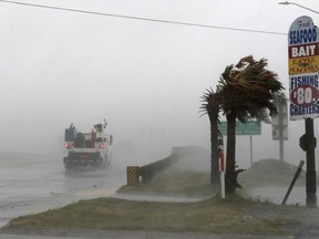 A work truck drives on Hwy 24 as the wind from Hurricane Florence blows palm trees in Swansboro N.C., Thursday, Sept. 13, 2018.