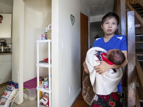In this Sept. 20, 2018 photo,Eh Htoo, holds her three-week-old baby while a city inspector, left examines her kitchen at the Yale Park Apartments in Omaha, Neb. Social service agencies are scrambling to help up to 500 refugees who may have to find new places to live because of the squalid conditions in their Nebraska apartment complex.