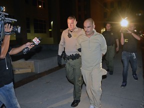 Bernalillo County Sheriff's Office Deputy Daniel Degraff walks Jaime Veleta Jr. to an awaiting car to be booked into Metropolitan Detention Center on murder charges in the death of Danny Baca in 2008, Wednesday, Sept. 5, 2018 in Albuquerque, N.M. Veleta faces charges of murder, kidnapping, aggravated burglary, tampering and conspiracy.