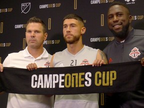 Toronto FC coach Greg Vanney, left to right, midfielder Jonathan Osorio and striker Jozy Altidore hold up the Campeones Cup scarf ahead of Wednesday's meeting with Mexico's Tigres UANL, in Toronto on Tuesday, Sept. 18, 2018.