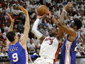 FILE - In this Saturday, April 21, 2018 file photo, Miami Heat guard Dwyane Wade (3) shoots and scores late in the fourth quarter as Philadelphia 76ers forward Dario Saric (9) and Joel Embiid (21) defend in Game 4 of a first-round NBA basketball playoff series in Miami. Wade is coming back to the Miami Heat, announcing Sunday, Sept. 16, 2018 that he's returning for a 16th and final NBA season. He basically spent the entirety of the last four months weighing his options, and retirement was an extremely real possibility in his mind.