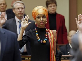 FILE - In this Tuesday, Jan. 3, 2017 file photo, State Rep. Ilhan Omar takes the oath of office as the 2017 legislature convened in St. Paul, Minn. Omar, a Muslim, is the nation's first Somali-American to be elected to a state legislature. Religion's role in politics and social policies is in the spotlight heading toward the midterm elections, yet relatively few Americans consider it crucial that a candidate be devoutly religious or share their religious beliefs, according to an AP-NORC national poll conducted Aug. 16-20, 2018.