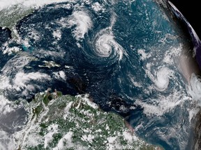 This enhanced satellite image made available by NOAA shows Tropical Storm Florence, center, in the Atlantic Ocean on Saturday, Sept. 8, 2018 at 2:45 p.m. EDT. (NOAA via AP)