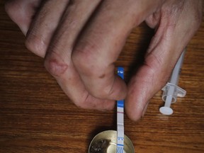 An addict prepares heroin, placing a fentanyl test strip into the mixing container to check for contamination, Wednesday Aug. 22, 2018, in New York. He said the test strips are hard to come by, but he's used them _ usually when he bought drugs from a new dealer. All those tests were positive. He said he took the drugs anyway, starting with a smaller dose called a "tester shot."