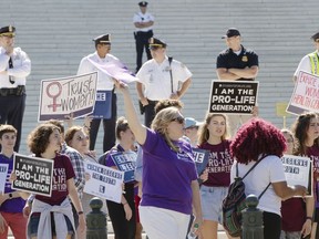 FILE - In this Monday, June 25, 2018 file photo, pro-choice and anti-abortion advocates hold signs as they demonstrate in front of the Supreme Court in Washington. Among those riveted by the drama of Brett Kavanaugh's Supreme Court nomination are the rival sides in America's abortion debate, each convinced that the nationwide right to abortion is at stake.