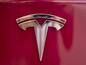 FILE - This Aug. 8, 2018, file photo shows a Tesla emblem on the back end of a Model S in the Tesla showroom in Santa Monica, Calif. Tesla is dropping two of the seven standard colors it had offered to customers to streamline production. In a tweet early Tuesday, Sept. 11, CEO Elon Musk said obsidian black and metallic silver will still be available, but at a higher cost. Tesla fans can still get solid black and "midnight silver metallic," as well as pearl white, deep blue metallic and red as standard color choices.