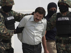 FILE - In this Feb. 22, 2014, file photo, Joaquin "El Chapo" Guzman is escorted to a helicopter in handcuffs by Mexican navy marines at a navy hanger in Mexico City, Mexico. A U.S. judge has rejected a request to put off the trial of notorious Mexican drug lord Guzman. Lawyers for Guzman told Judge Brian Cogan at a hearing Thursday, Sept. 20, 2018, that they needed more time to review a mountain of evidence in the drug-trafficking case.